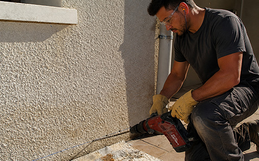 Homme qui fait des trous dans le bas du mur
